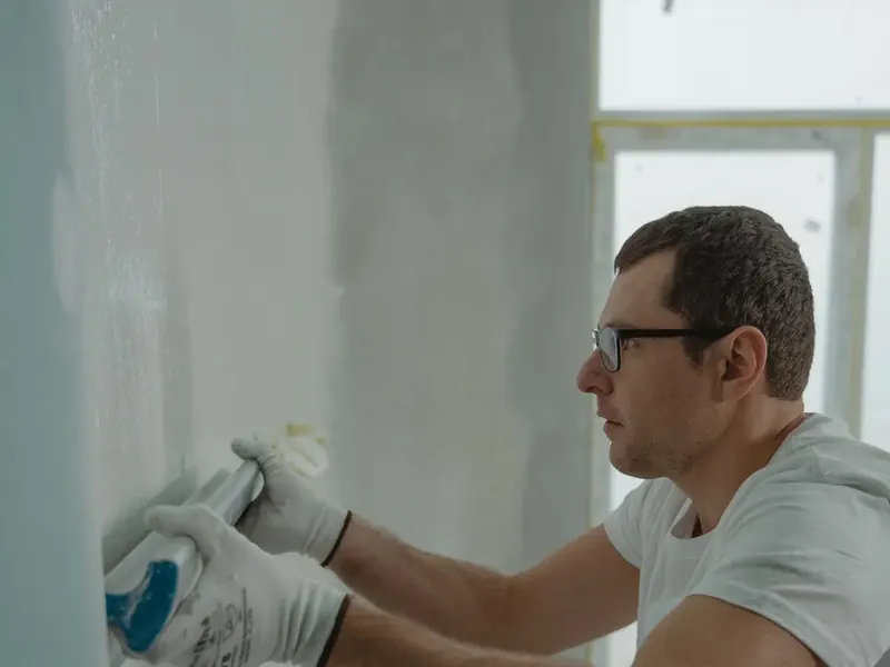 Drywall worker applying joint compound during a residential interior finish.